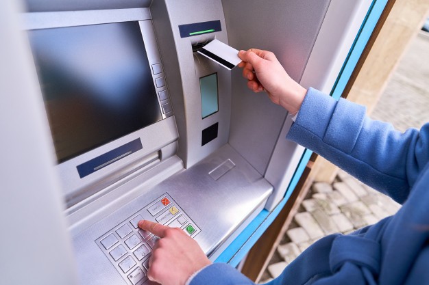 a pessoa insere um cartao de credito plastico no banco atm e disca um codigo pin no teclado para sacar dinheiro 122732 2944