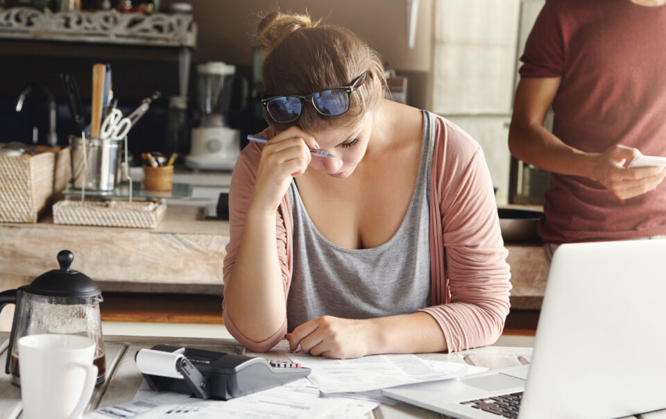 depressed couple facing credit problem stressed wife looking exhausted while doing accounts at home trying hard to cut family expenses holding pen and making necessary calculations on calculator