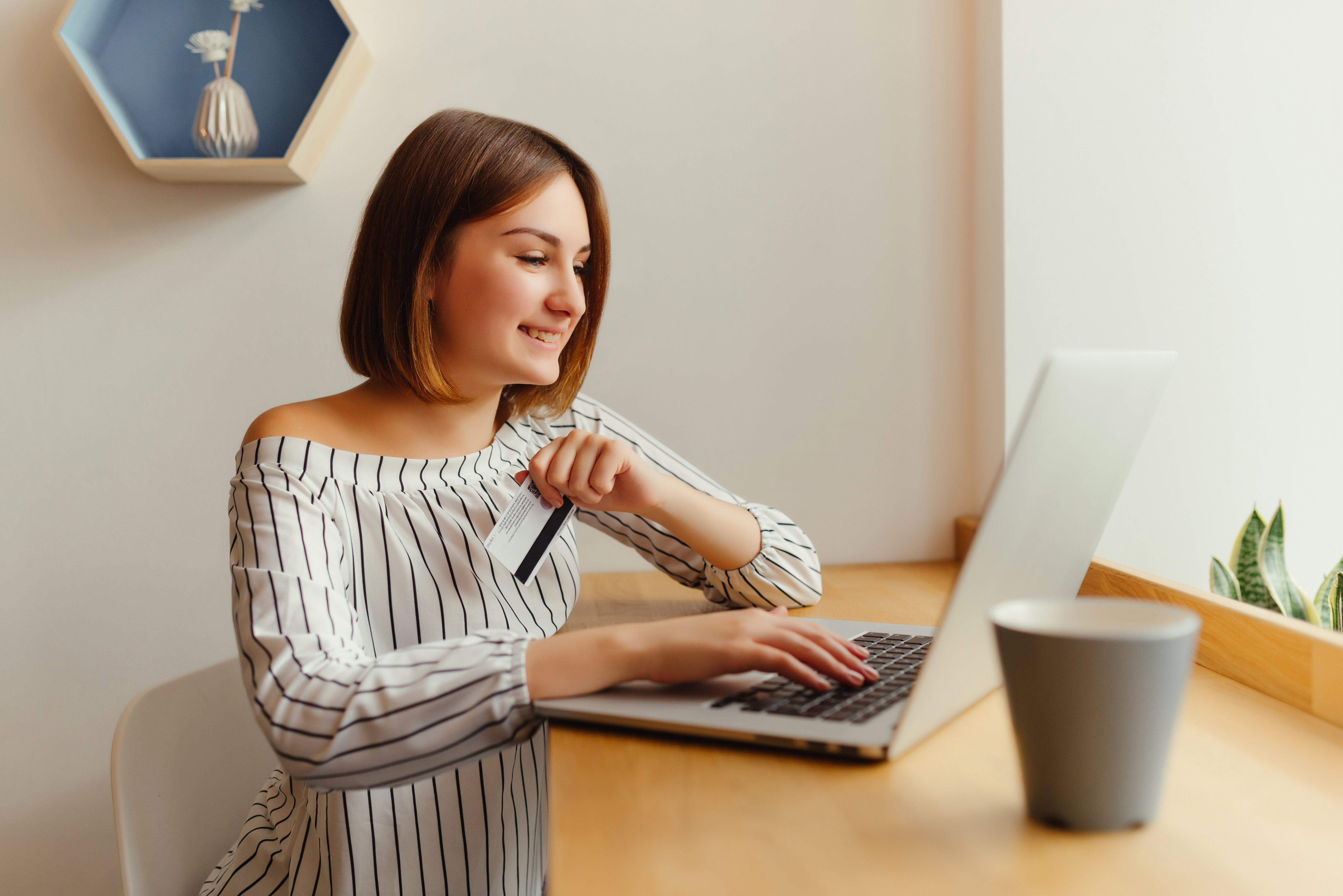 young happy female holding credit card and using laptop computer