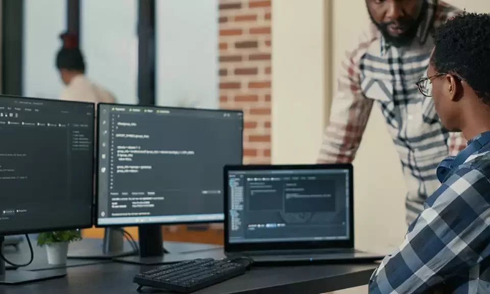 focused software developer writing code laptop looking multiple screens with programming language is interrupted by colleague coder asking advice programmers doing online cloud computing 1024x576 1