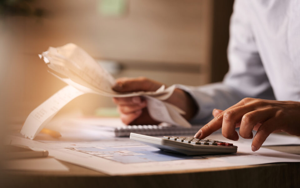 closeup economist using calculator while going through bills taxes office