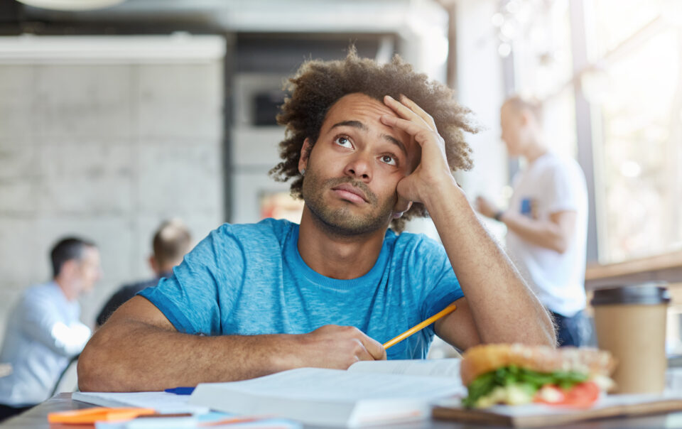 knowledge education unhappy afro american university student wearing blue t shirt looking up with questionable frustrated expression feeling tired while working home assignment cafe