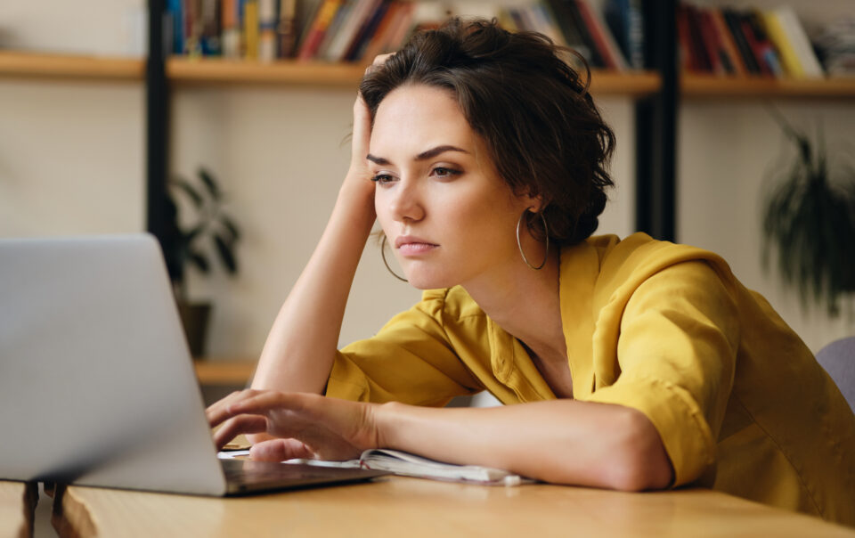 young upset woman sitting desk tiredly working new project with laptop modern office