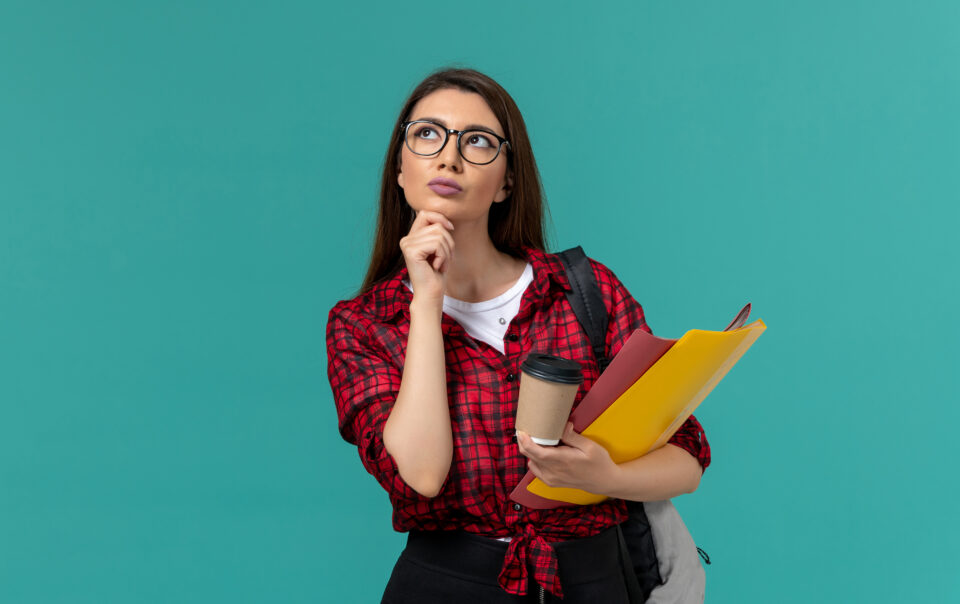 front view female student wearing backpack holding files coffee thinking light blue wall