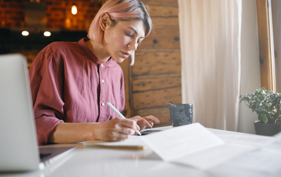 pensive young office worker checking documentation working from home remotely serious woman reading report sitting table with laptop